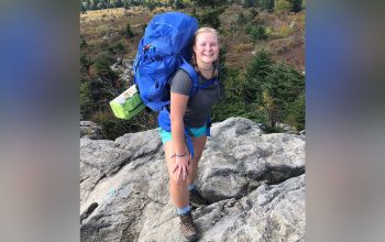 Frances Reed ’22 smiles atop a Rocky Mountain overlooking trees below.