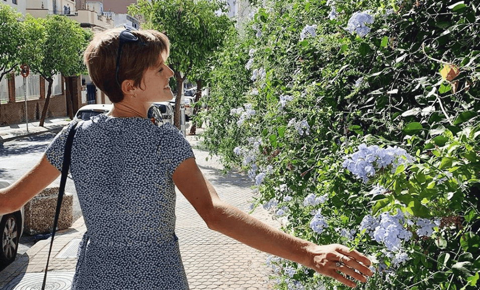 Sally Sasz smiling next to flowers.