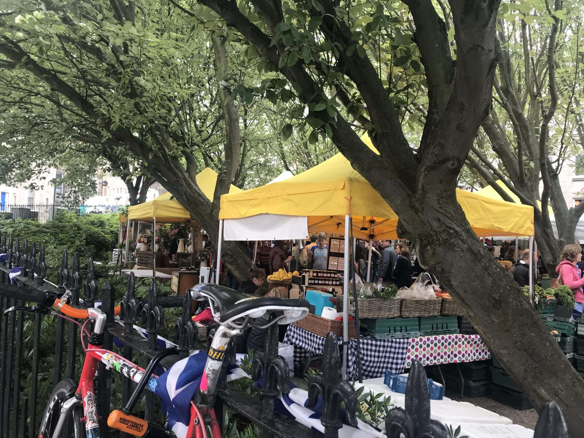 People browse the market stands under yellow tents at the Stockbridge Market. 