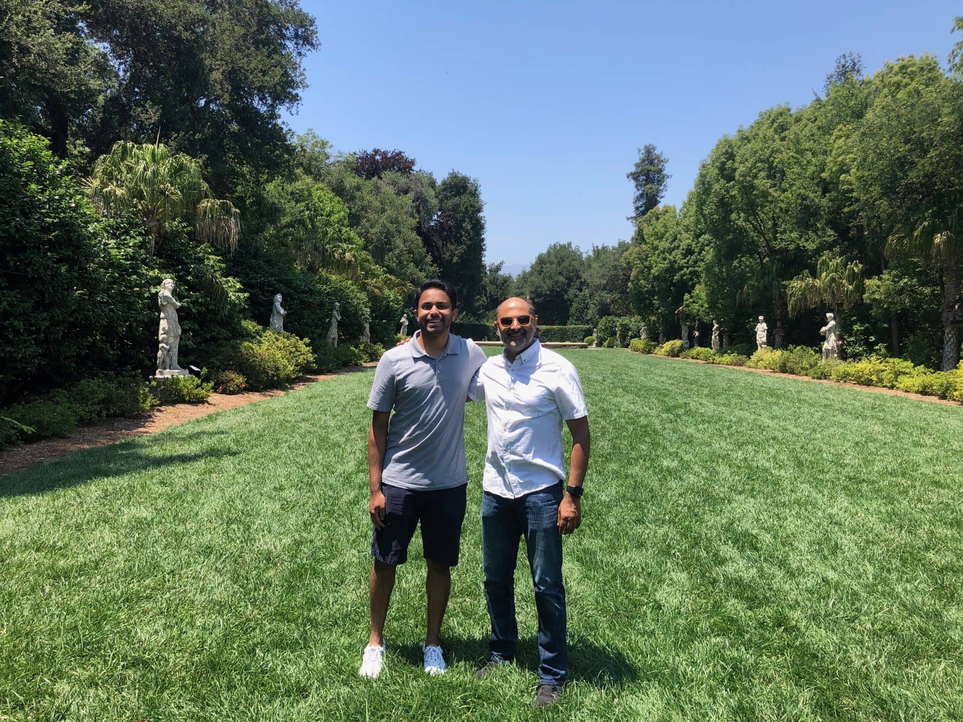 Shivam and Deepu outside in a field with trees on both sides.
