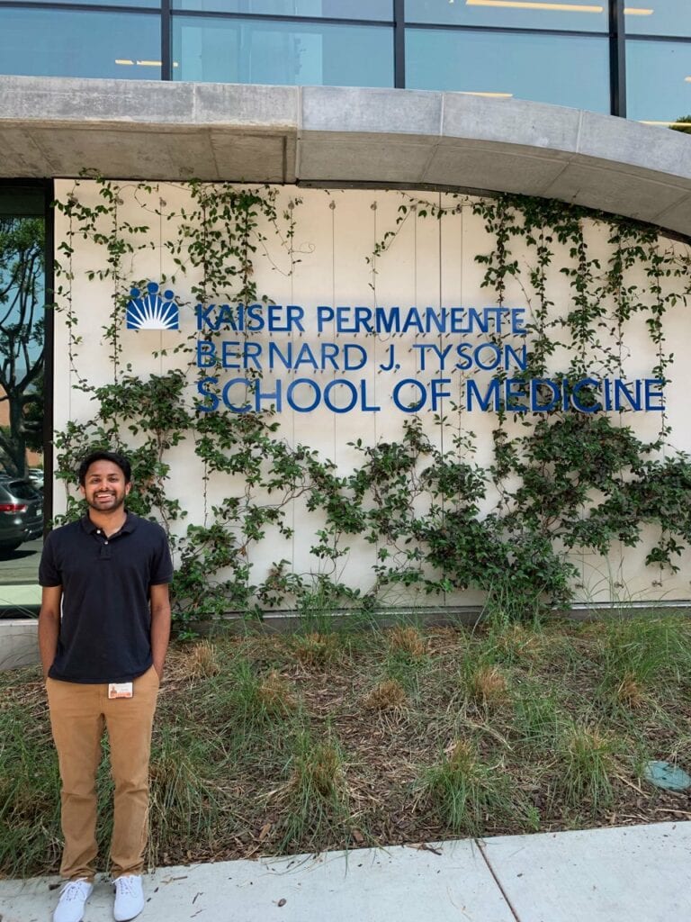 Shivam stands in front of the KPSOM building outside.