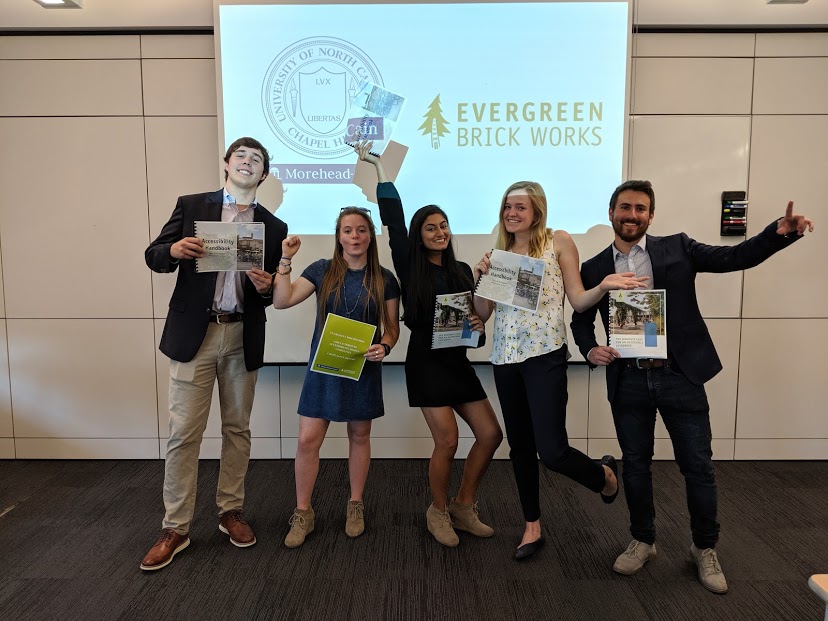 The group of scholars stand in front of their presentation screen.