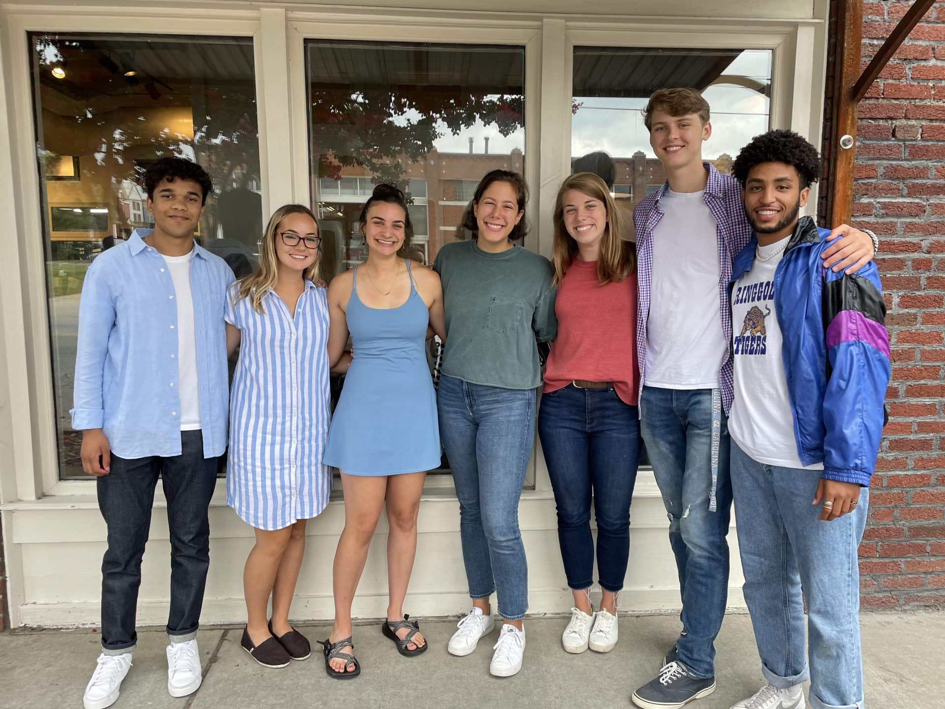 A group of scholars smile for a photo outside.