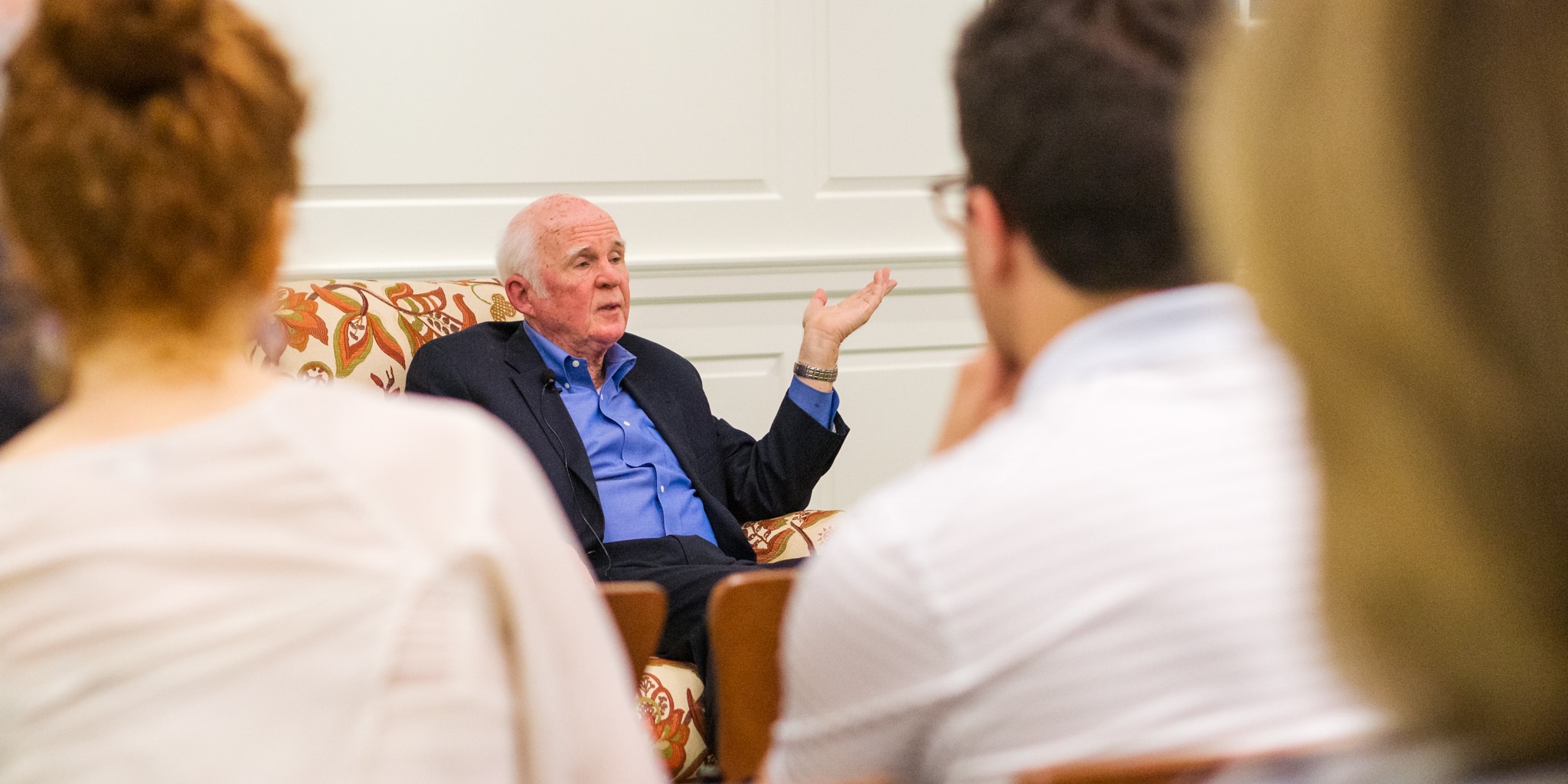 Taylor Branch sitting in chair speaking to a group of people.