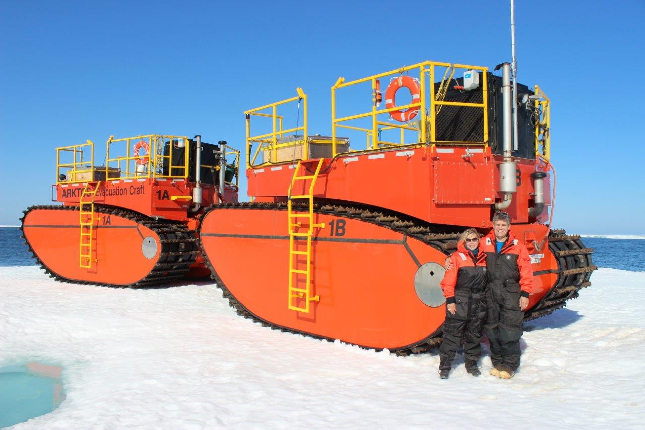 Two people standing in front of two ARKTOS watercrafts in the snow.