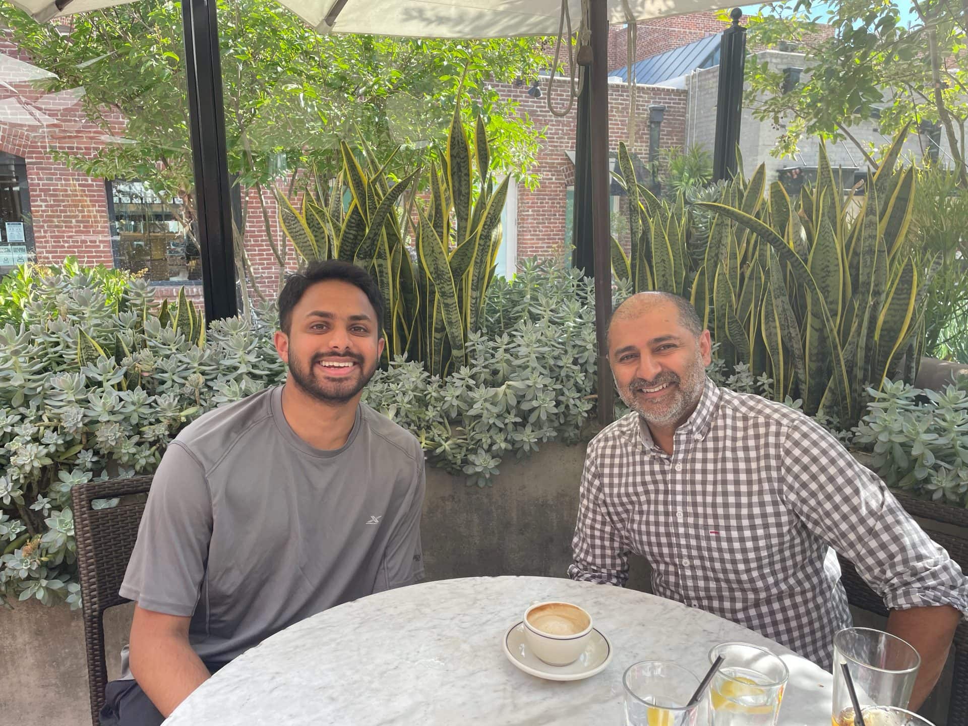 Shivam and Deepu sitting at a restaurant table outside.