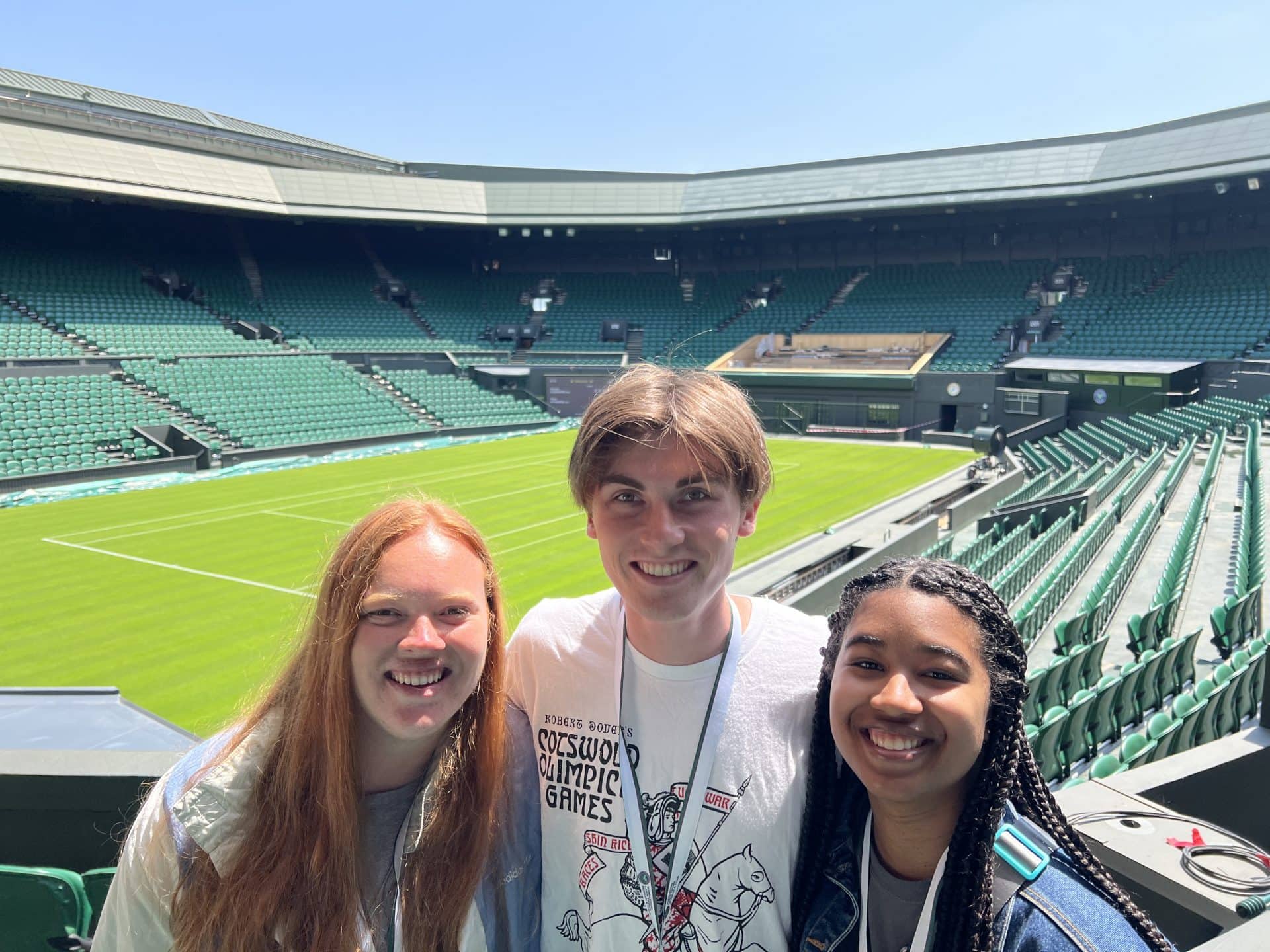 Three people smiling in the Olympic Games, capturing a joyful moment together.