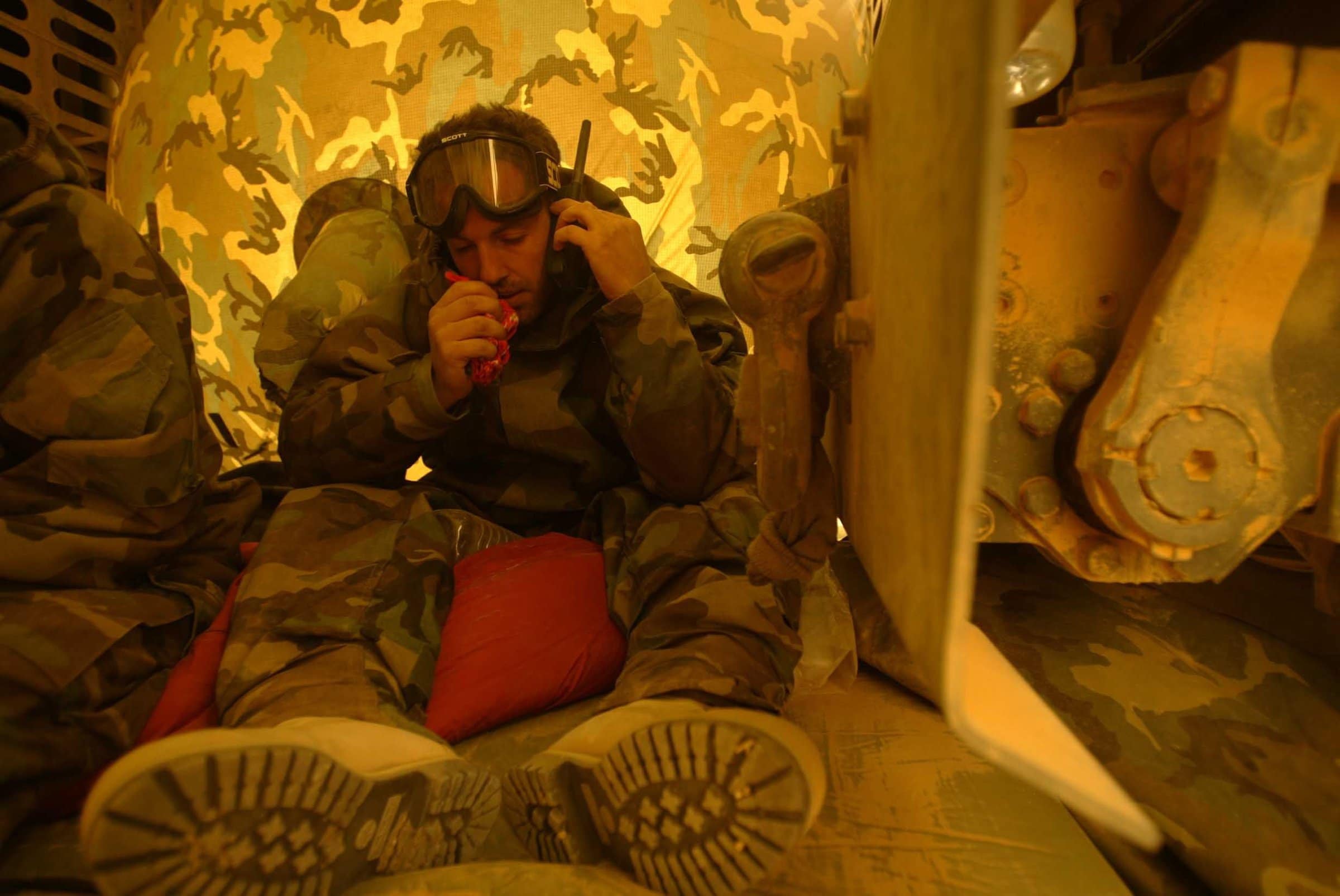 Luke speaks into a walkie-talkie wearing camouflage while seated.