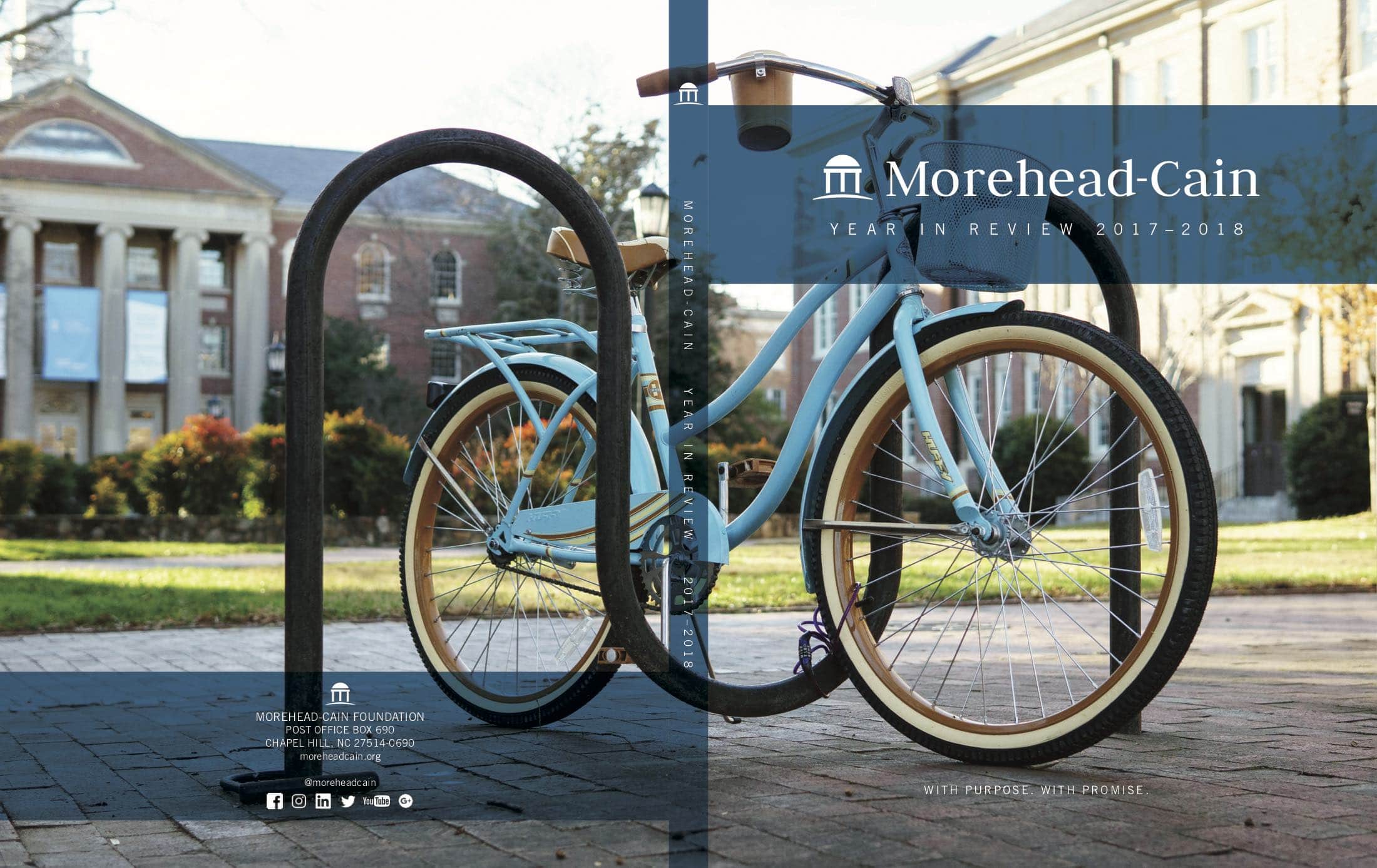 Front cover of the Year in Review 2017–2018. There is a blue bicycle outside some campus buildings. The Morehead-Cain logo is transposed on the image. 