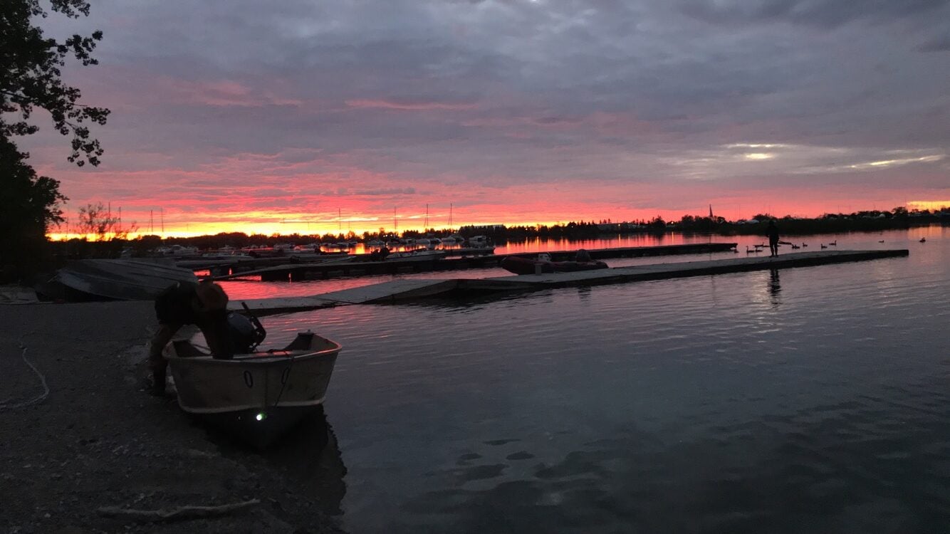 Sunrise over Ontario Lake. Boats are anchored by the beach.