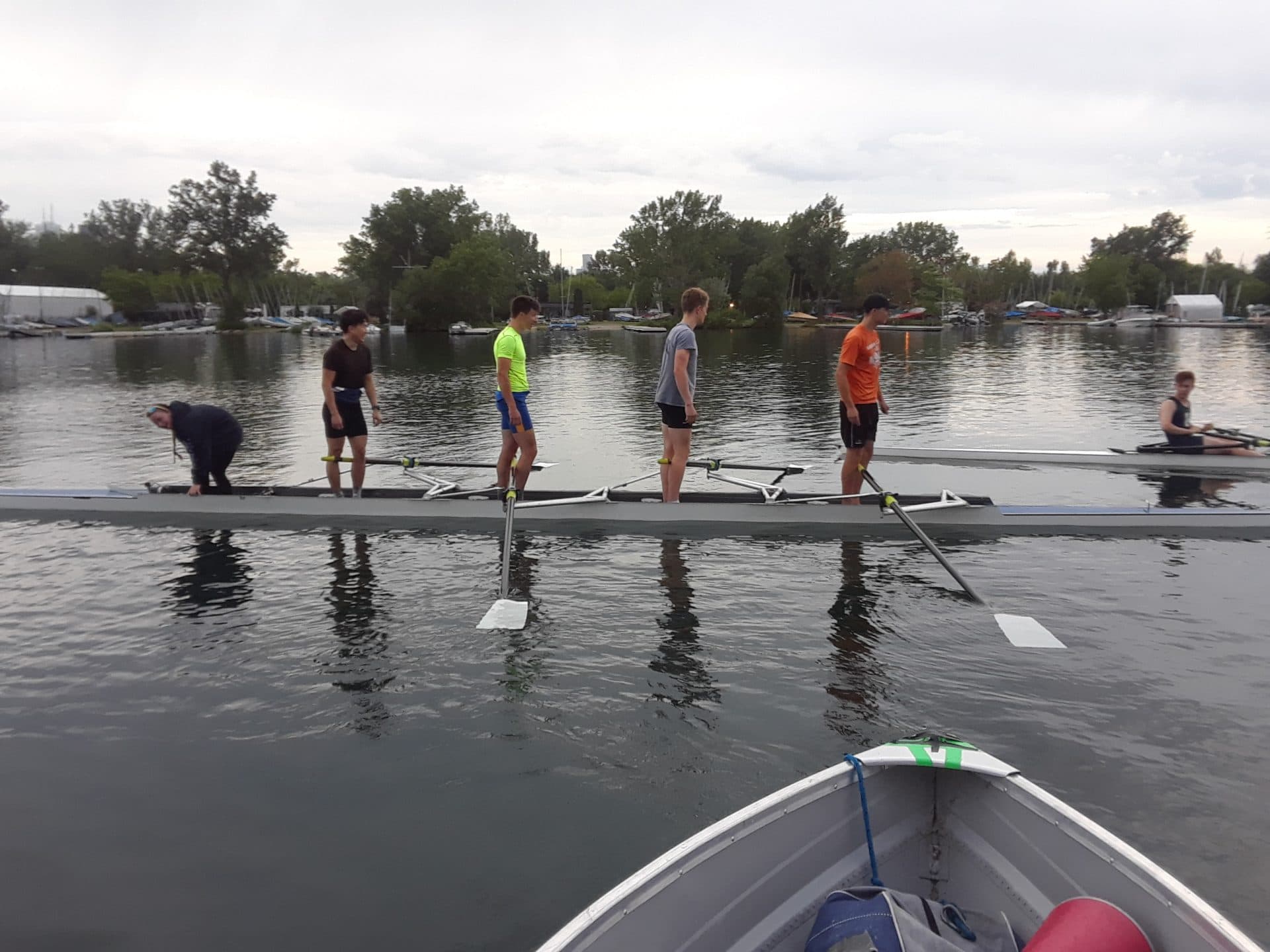 Four people stand on rowing boat, preparing to set off for their practice.