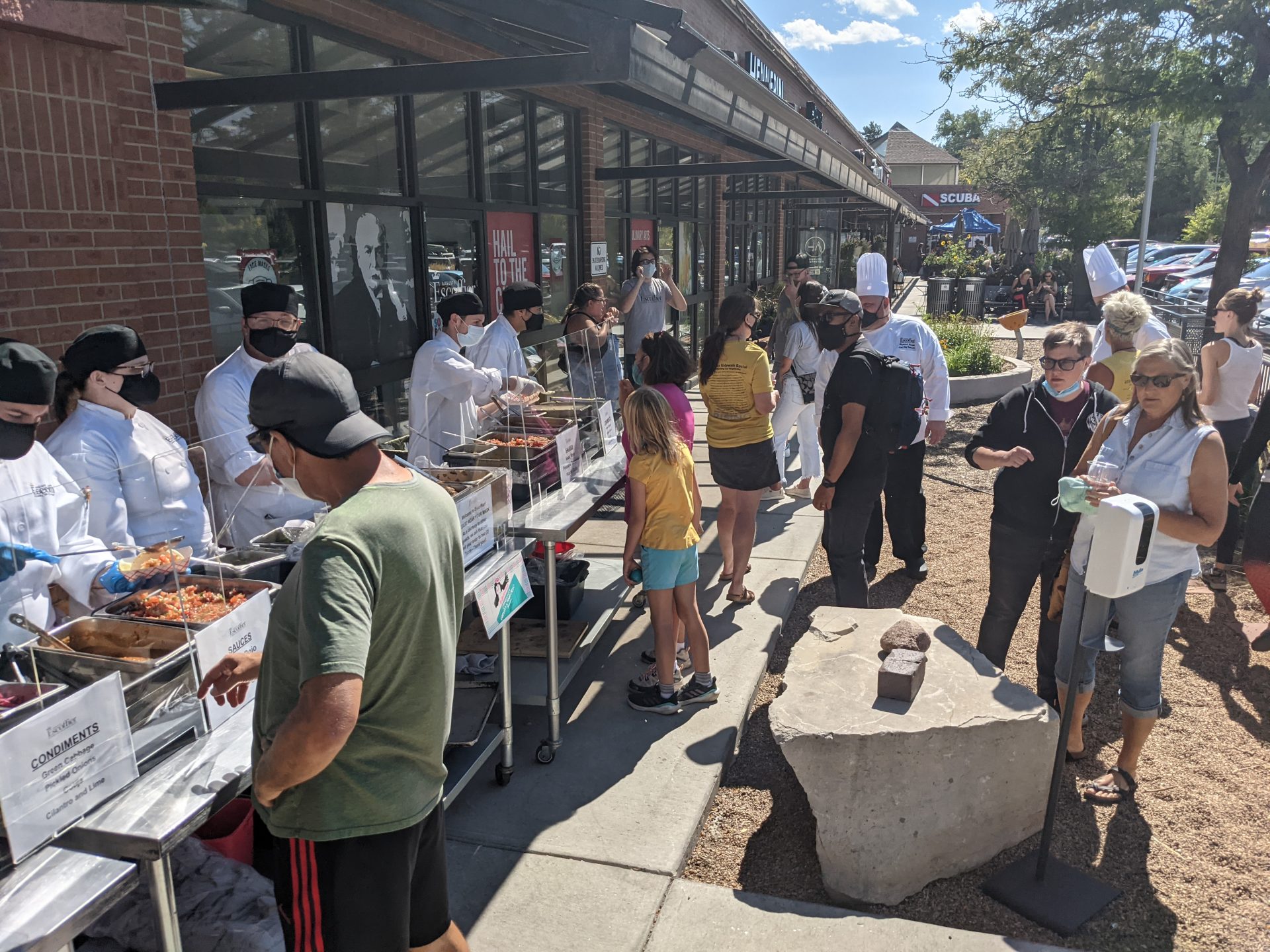 A group of people outside stand around a buffet line.