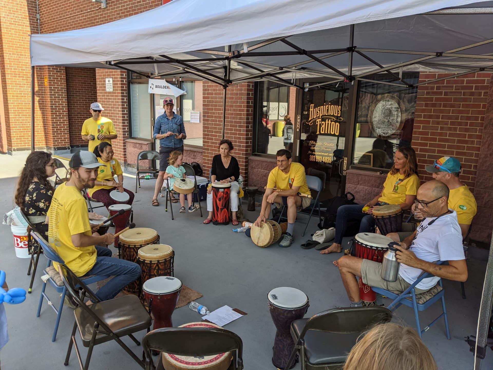 A group of people in circle with drums plan percussion music.