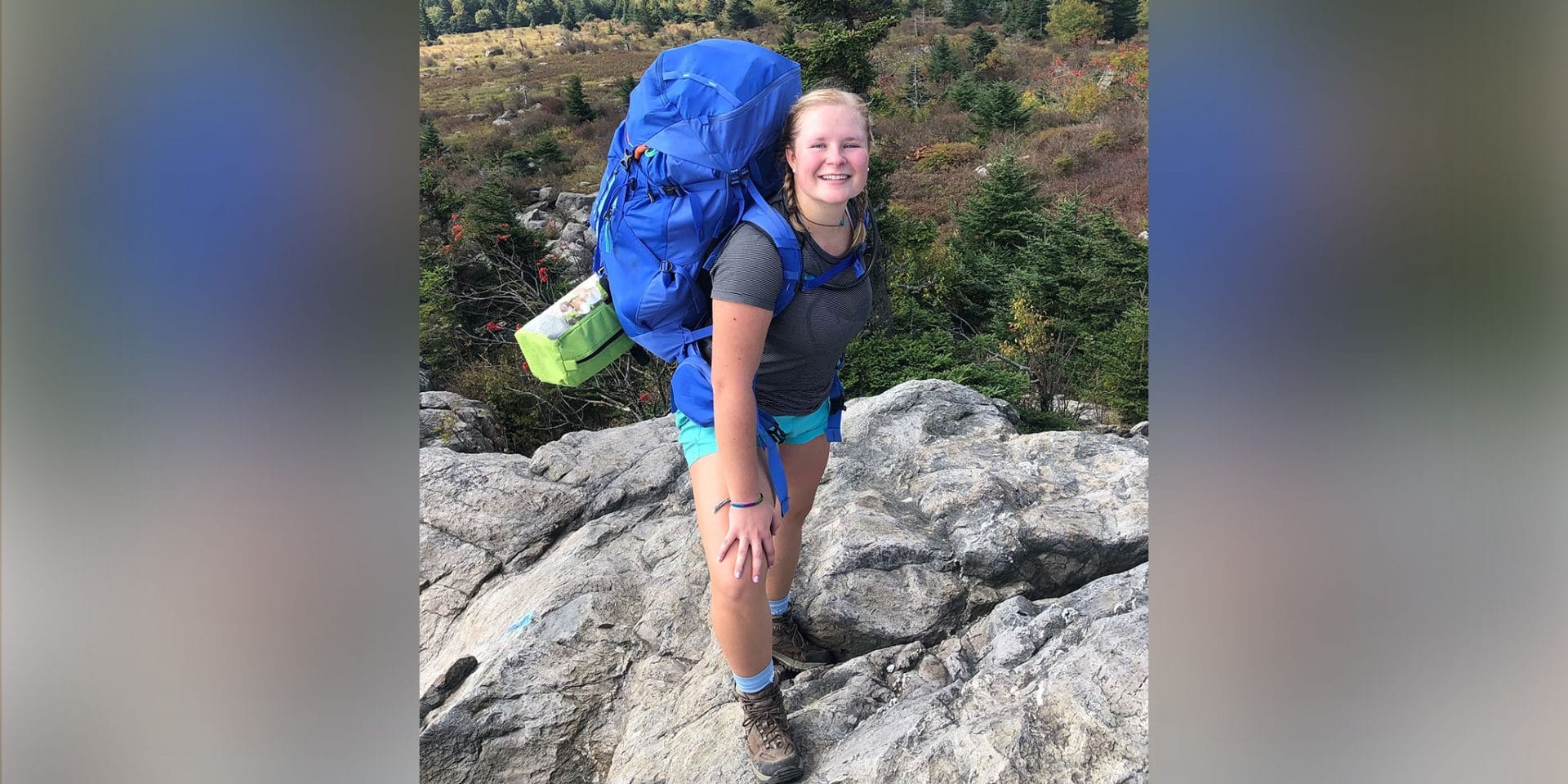 Frances Reed ’22 smiles atop a Rocky Mountain overlooking trees below.