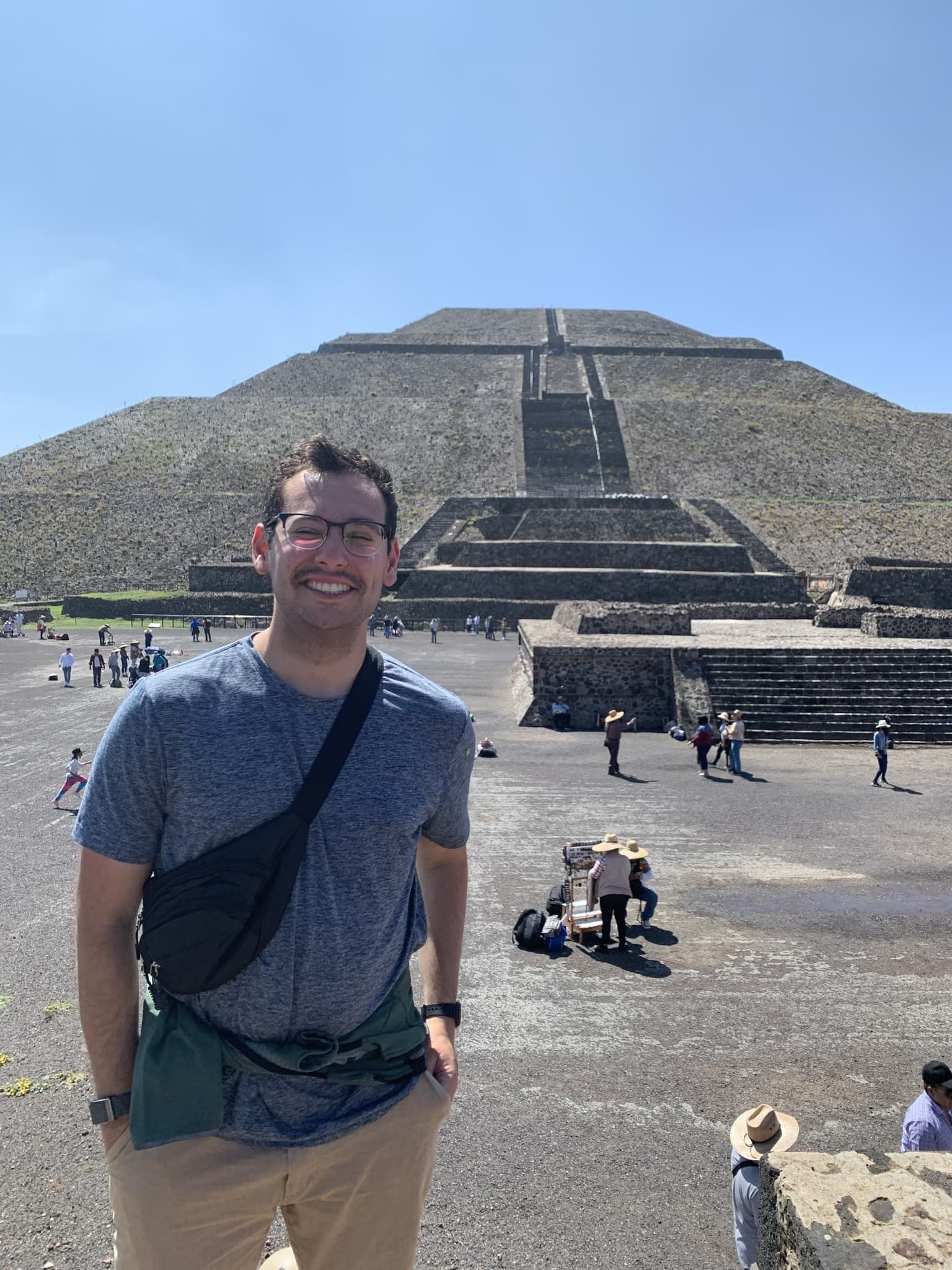 A man standing in front of a pyramid, showcasing the grandeur of ancient architecture.