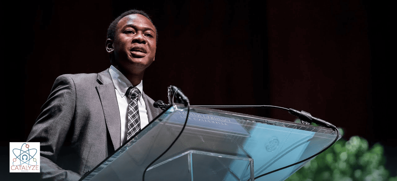 Headshot of Bradley Opere ’17 speaking at the mic behind a podium onstage.