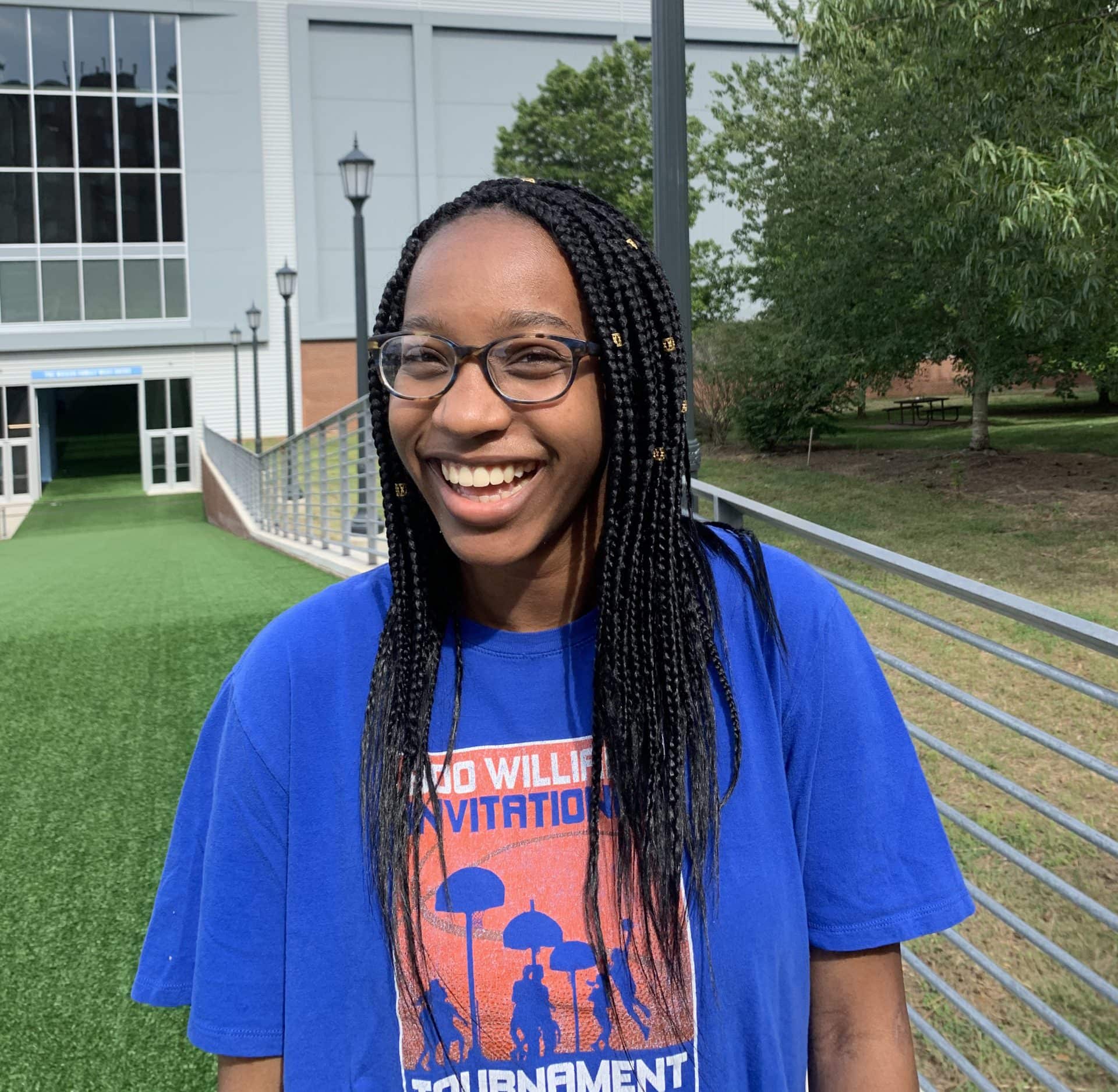Senam Adedze ’23 smiles for the camera wearing a blue t-shirt outside.