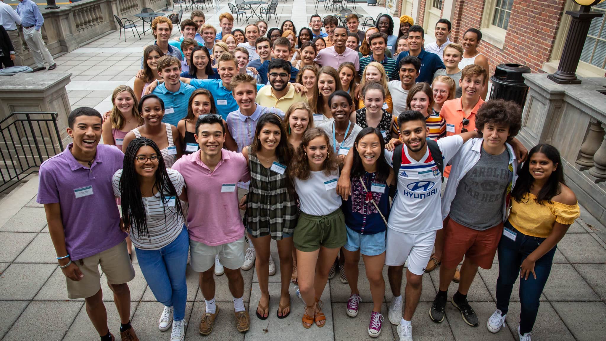 A group of young people smiling and posing for a photo on a sidewalk, capturing a joyful moment together.