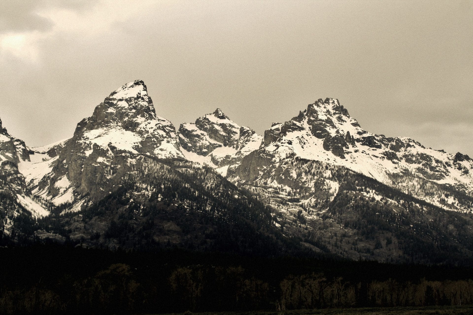 Grey skies overhang snowcapped mountains.