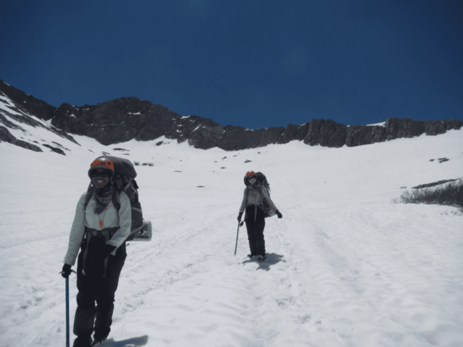 Two people are cross country skiing in snow.