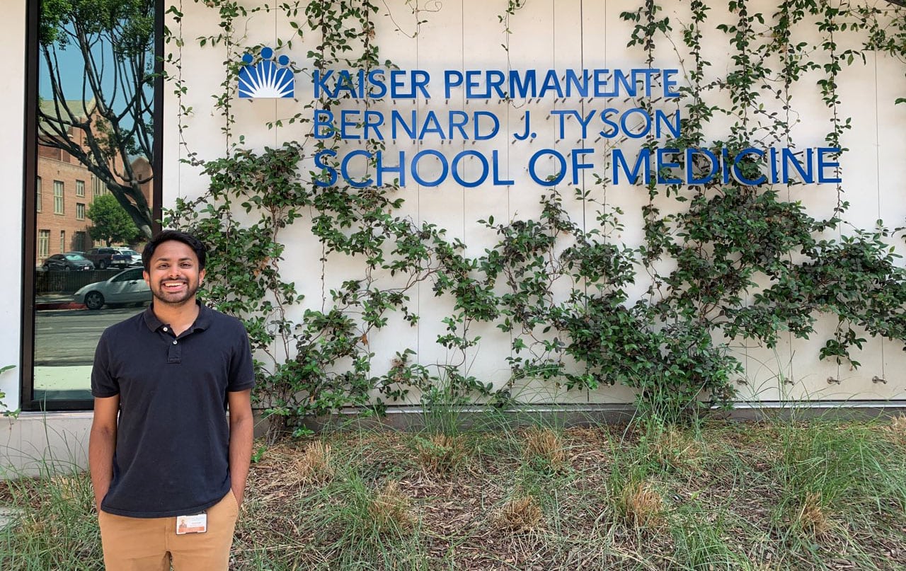 Shivam outside posing in front of the building for Kaiser Permanente Bernard J. Tyson School of Medicine.