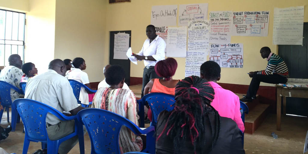 A man speaking with a group of adults in a classroom.