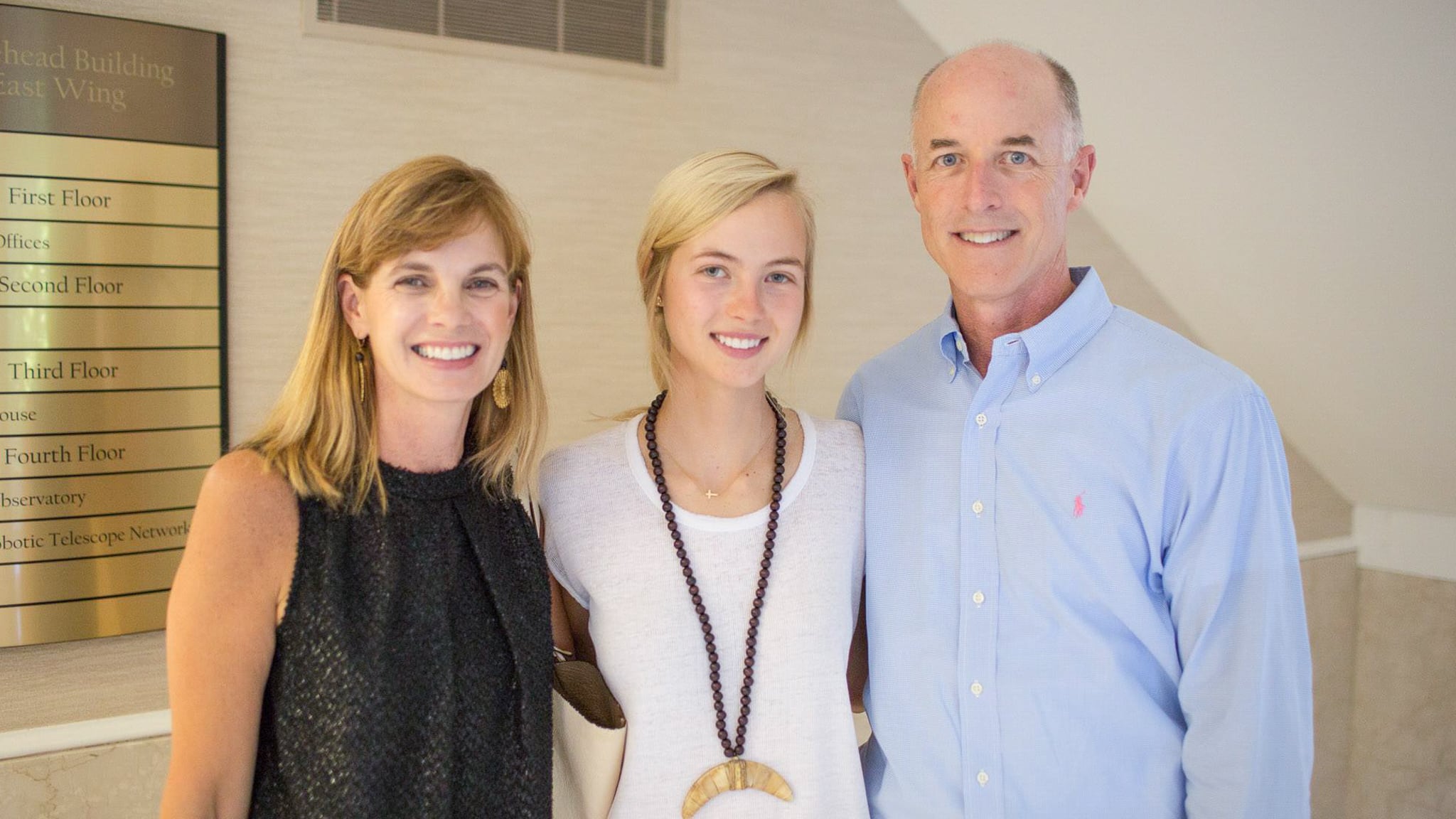 Three people smile at the camera inside the Morehead-Cain Foundation.
