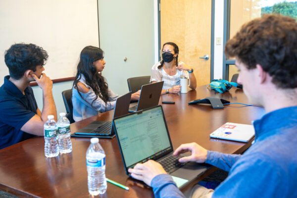 Three Morehead-Cain Scholars sit at a conference table to conduct an ethnographic interview with a Land of Sky employee