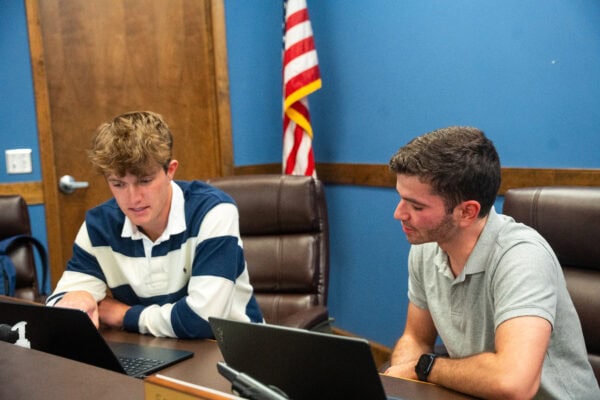 Two male college students look at laptops in the Town of Black Mountain office.