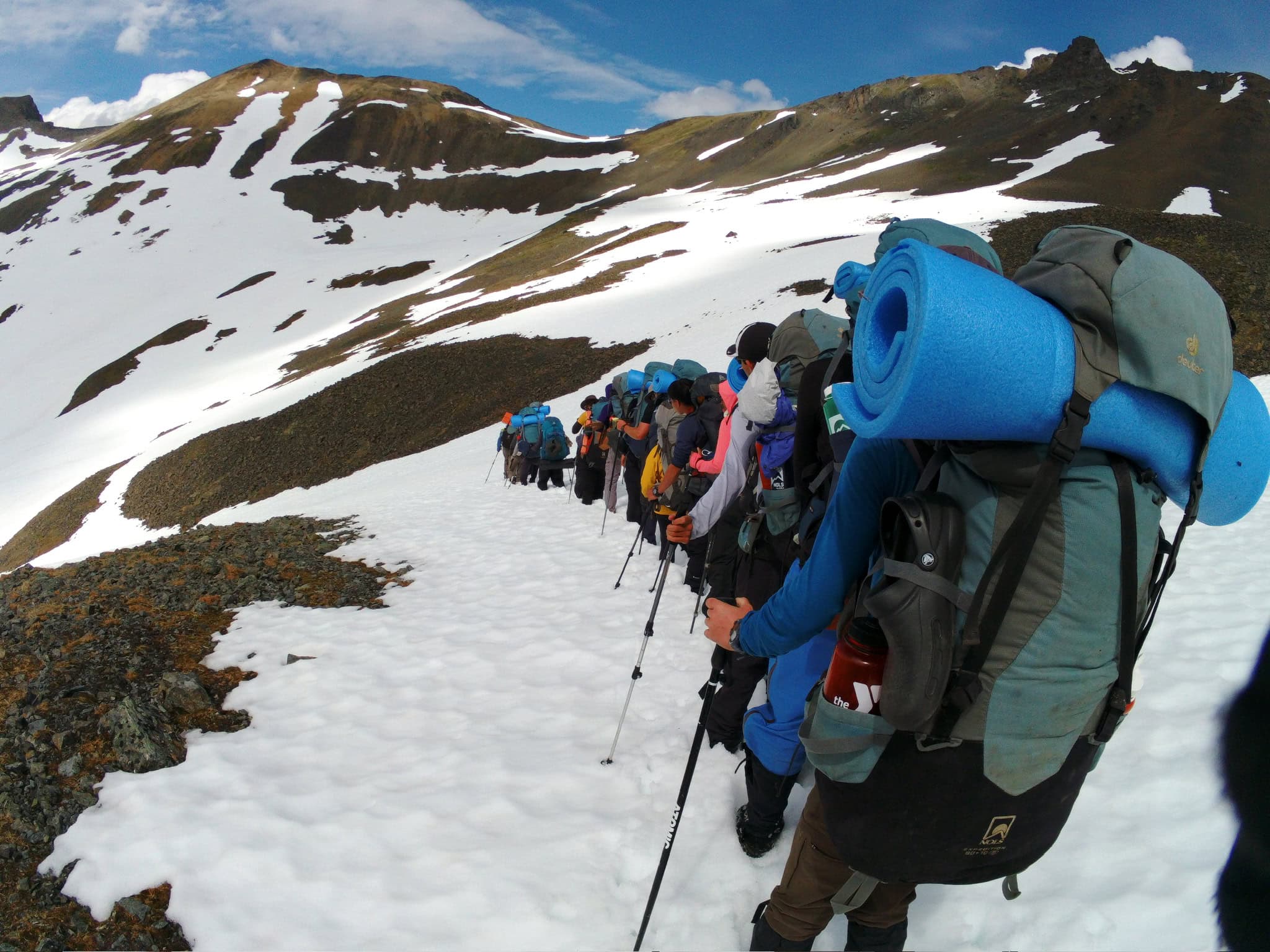 Students backpacking through snow-covered mountains