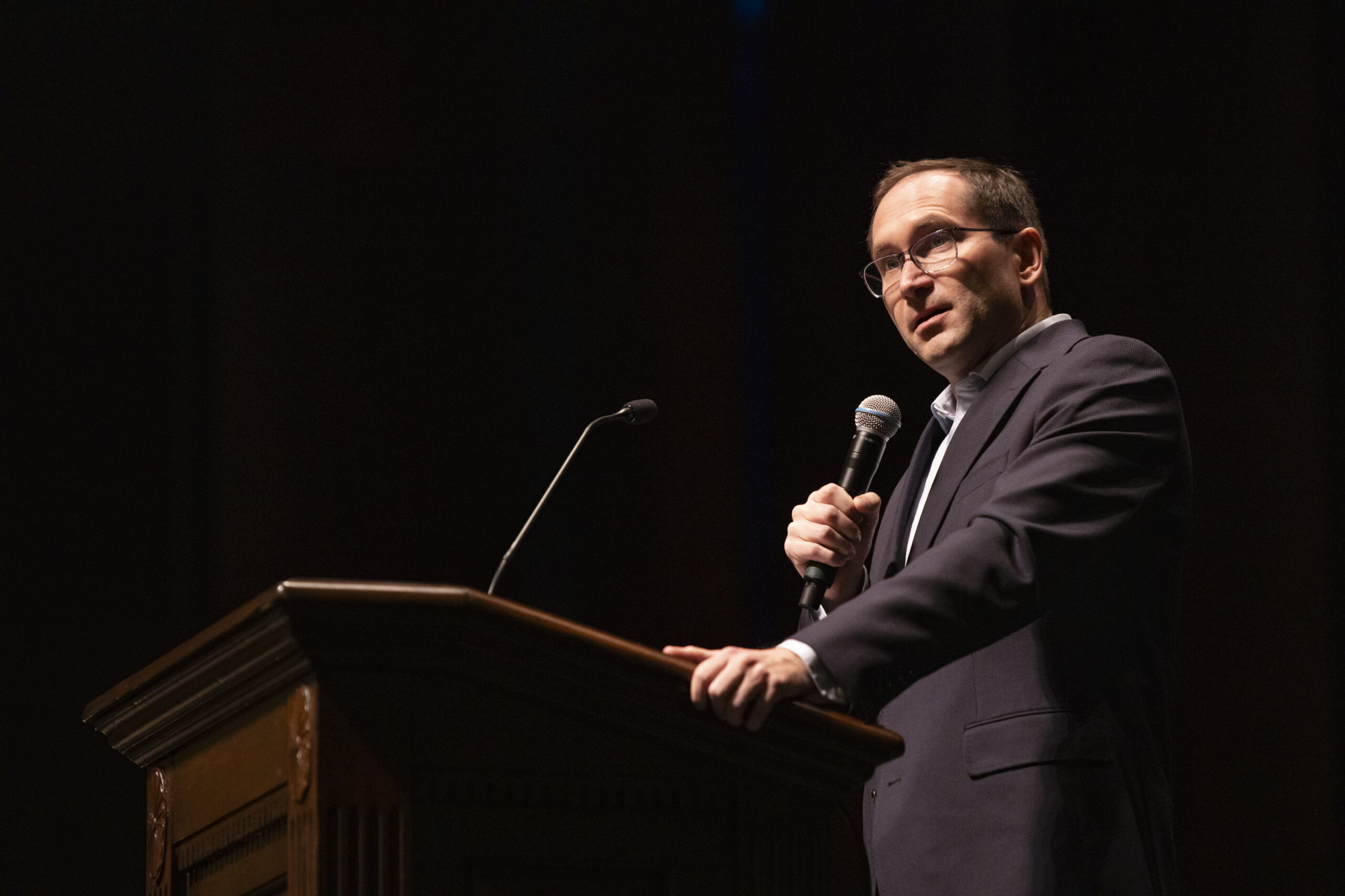 Chris Bradford speaking behind a podium on stage.