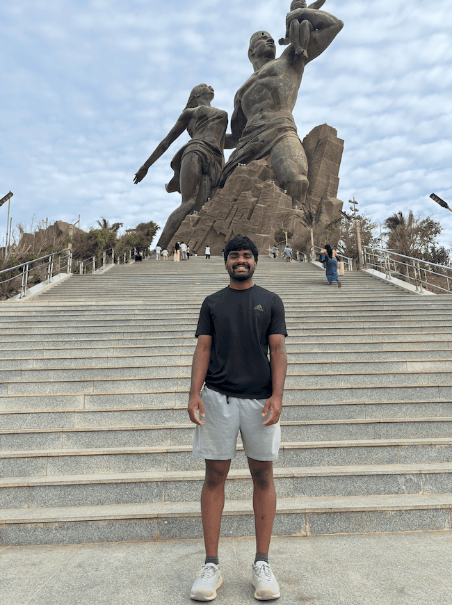 Suhan Asaigoli ’27 stands at the base of the African Renaissance Monument in Dakar, Senegal, with the monument’s statues visible behind him.