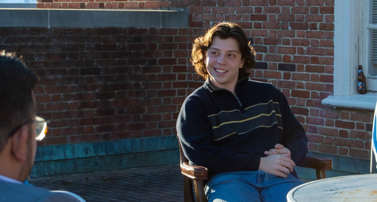 Man talking with friend on outside patio.